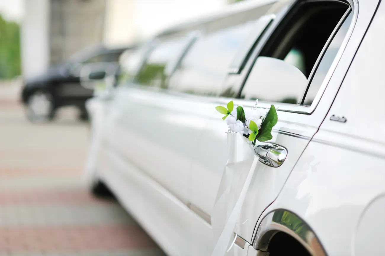 Weiße Stretchlimousine mit weißem Blumenschmuck und Schleife am Türgriff