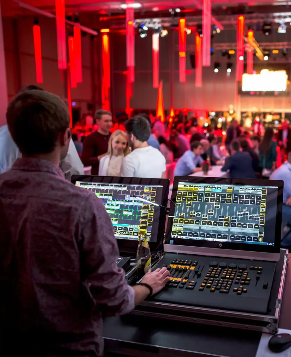 Techniker am Mischpult vor einem rot beleuchteten Event im Hangar