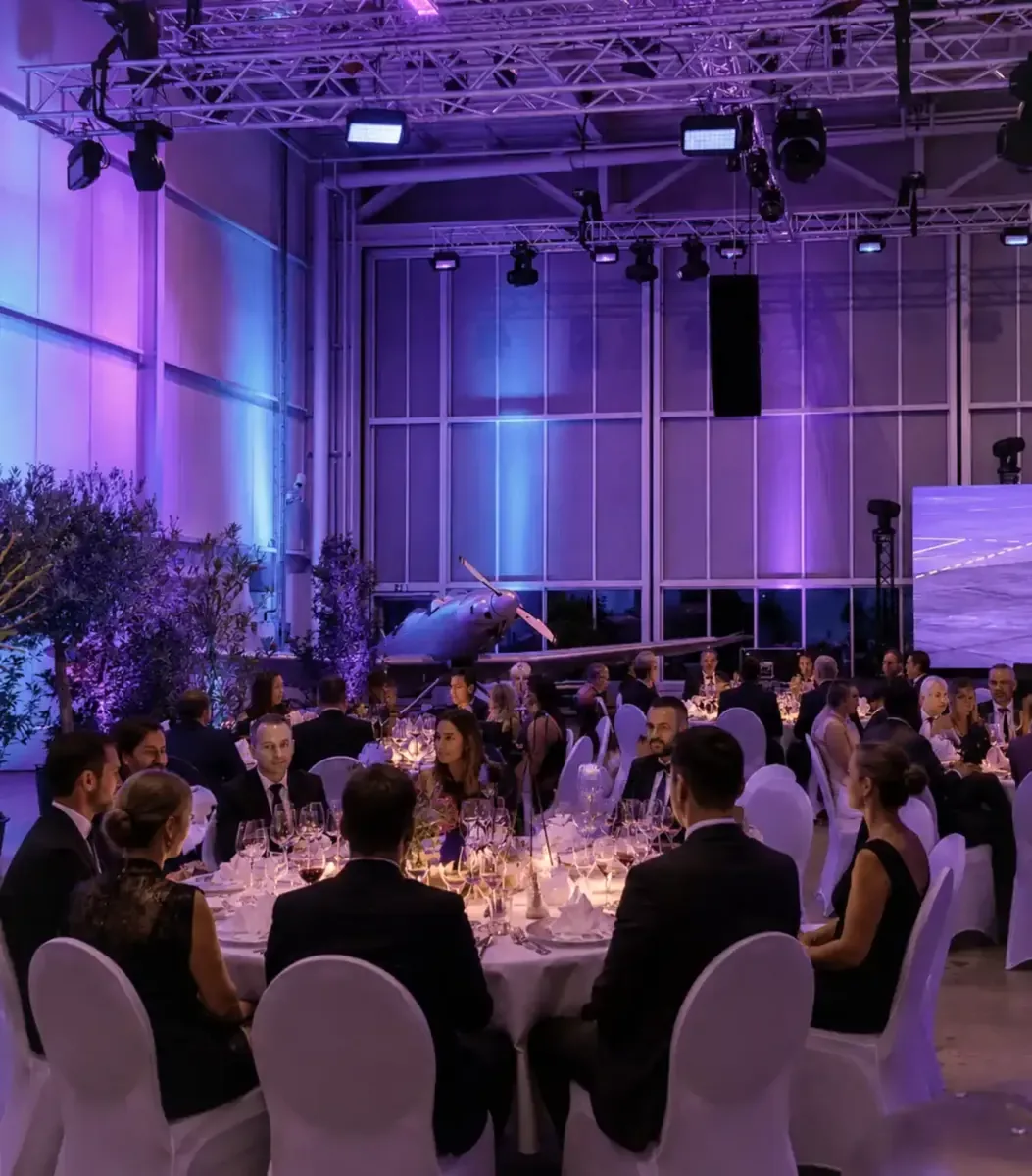 Festliches Galadinner mit runden Tischen und Kerzenlicht im Hangar bei aircraft events