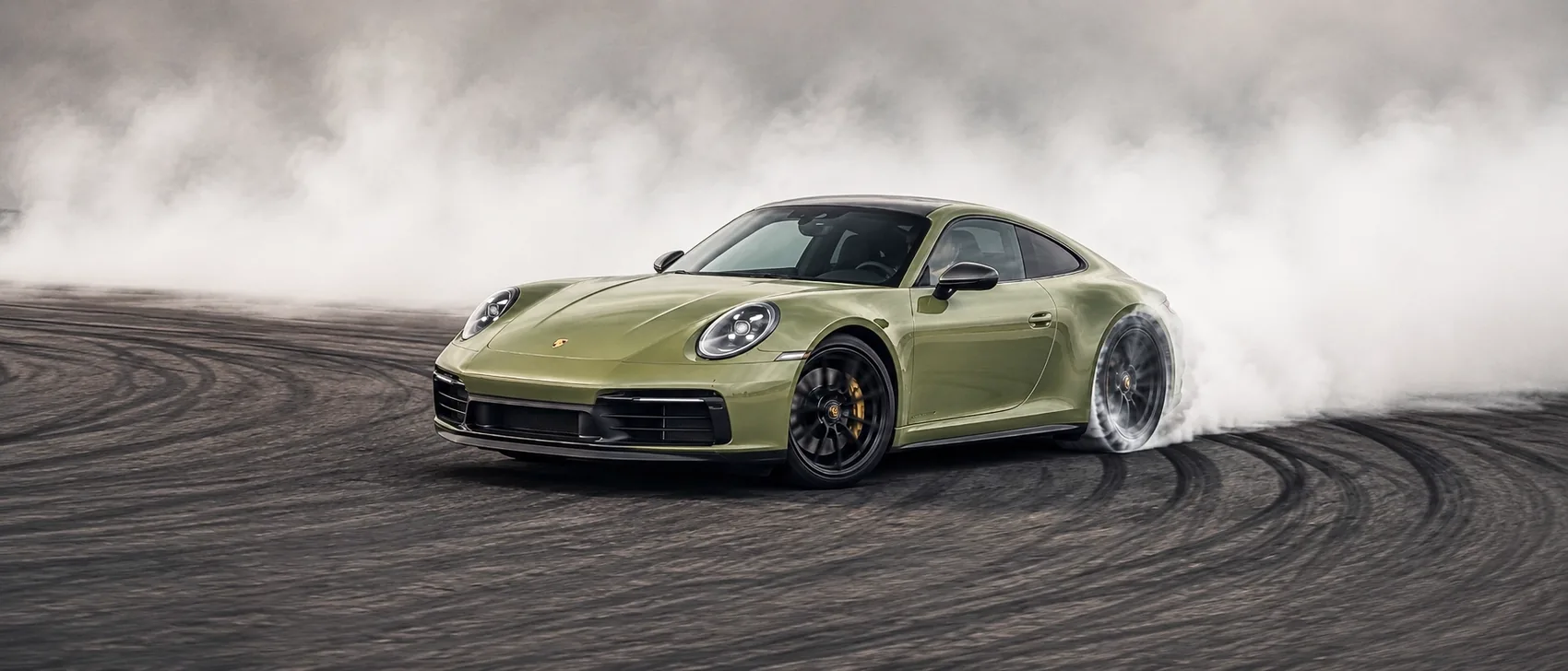 Grüner Porsche 911 beim kontrollierten Drift mit aufsteigendem Reifenrauch